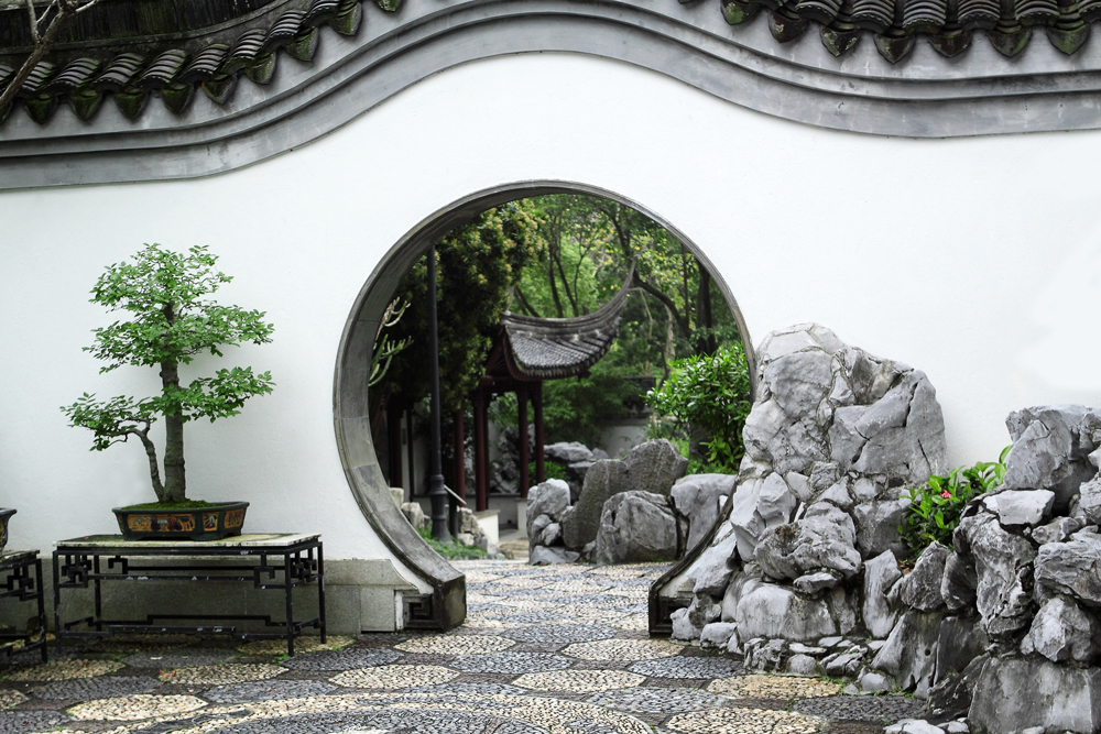 moon gate with rocks and bonsai tree